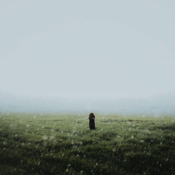 Person meditating peacefully outdoors with soft natural light.